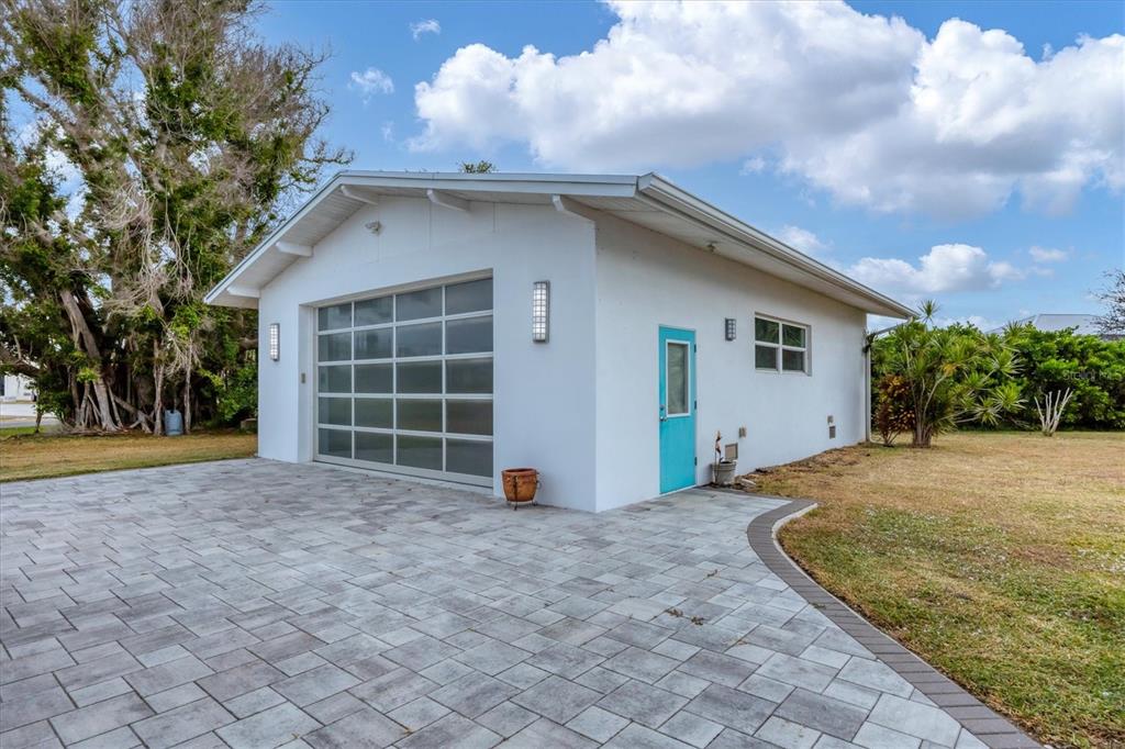 A white detached garage features a modern glass sectional door and a bright blue side door — 45 CAPE HAZE DRIVE, PLACIDA, FL