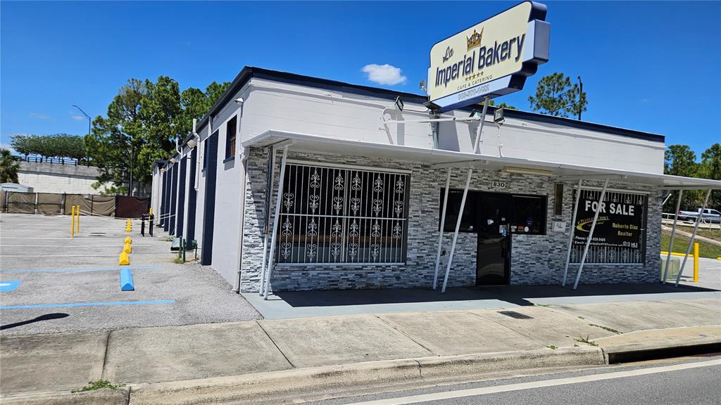 A single-story commercial building with a stone facade, security bars on windows, and a parking lot — 830 E MAIN STREET, LAKELAND, FL