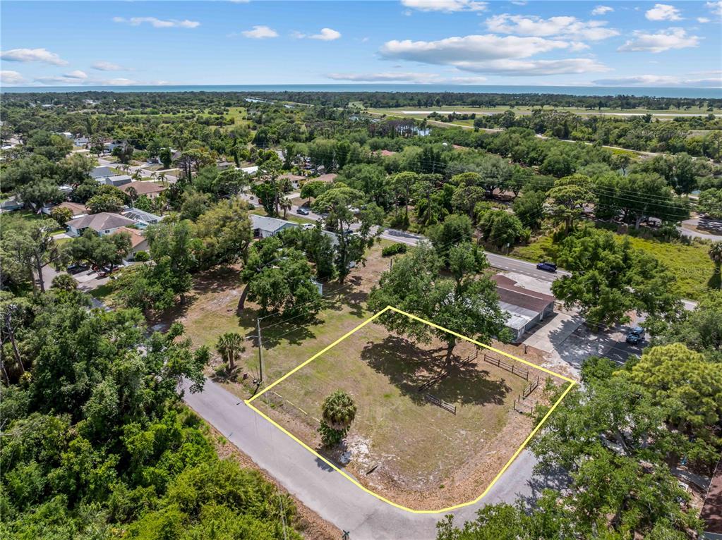 An aerial view shows a vacant, grass-covered lot outlined in yellow near a paved road — DAWN DRIVE, VENICE, FL