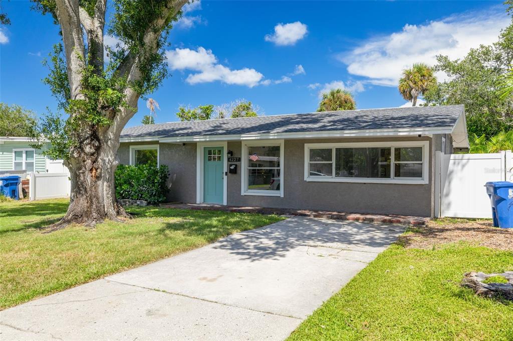 A single-story house with a gray exterior, a light blue front door, and a concrete driveway — 4227 HARRISBURG STREET NE, ST PETERSBURG, FL