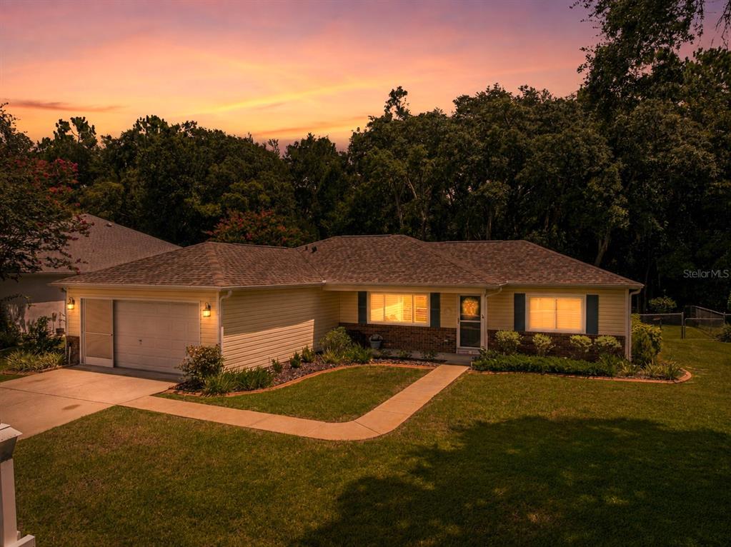 A single-story house with a garage and brick accents sits under a sunset sky — 14366 SW 115TH CIRCLE, DUNNELLON, FL