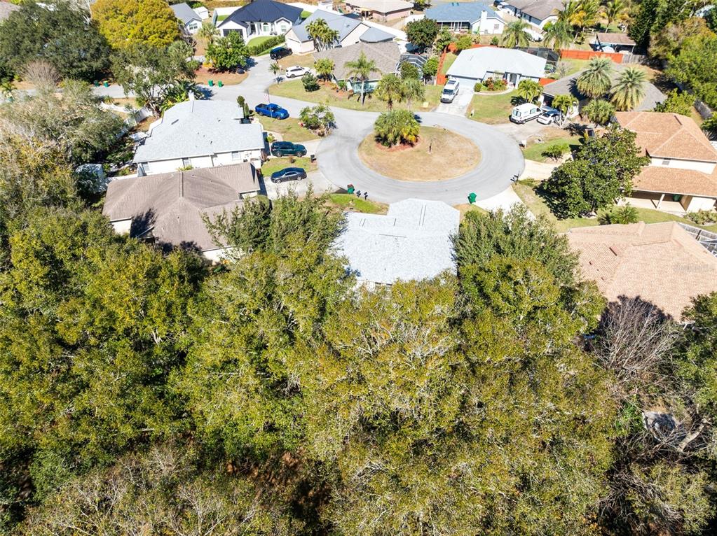 An aerial view shows a suburban cul-de-sac surrounded by dense trees and residential homes — 703 SAMUEL CHASE LANE, WEST MELBOURNE, FL