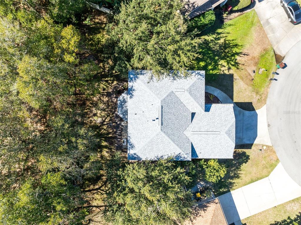 An aerial view shows a house with a gray shingled roof surrounded by trees — 703 SAMUEL CHASE LANE, WEST MELBOURNE, FL