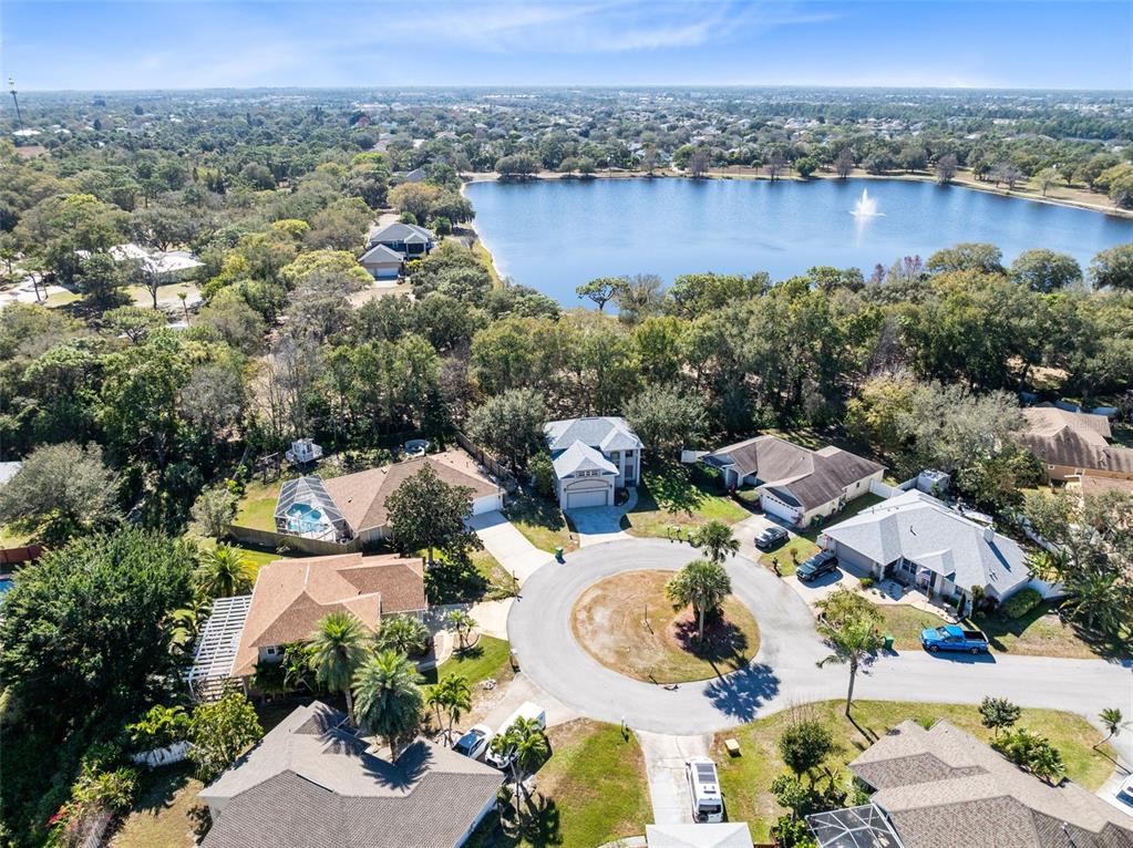An aerial view shows a suburban cul-de-sac with several houses near a large lake — 703 SAMUEL CHASE LANE, WEST MELBOURNE, FL