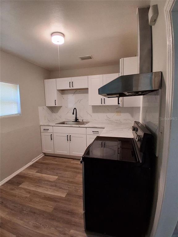 A kitchen features white cabinets, marble-look countertops, a black faucet, and a black range — 506 N MACDILL AVENUE, TAMPA, FL