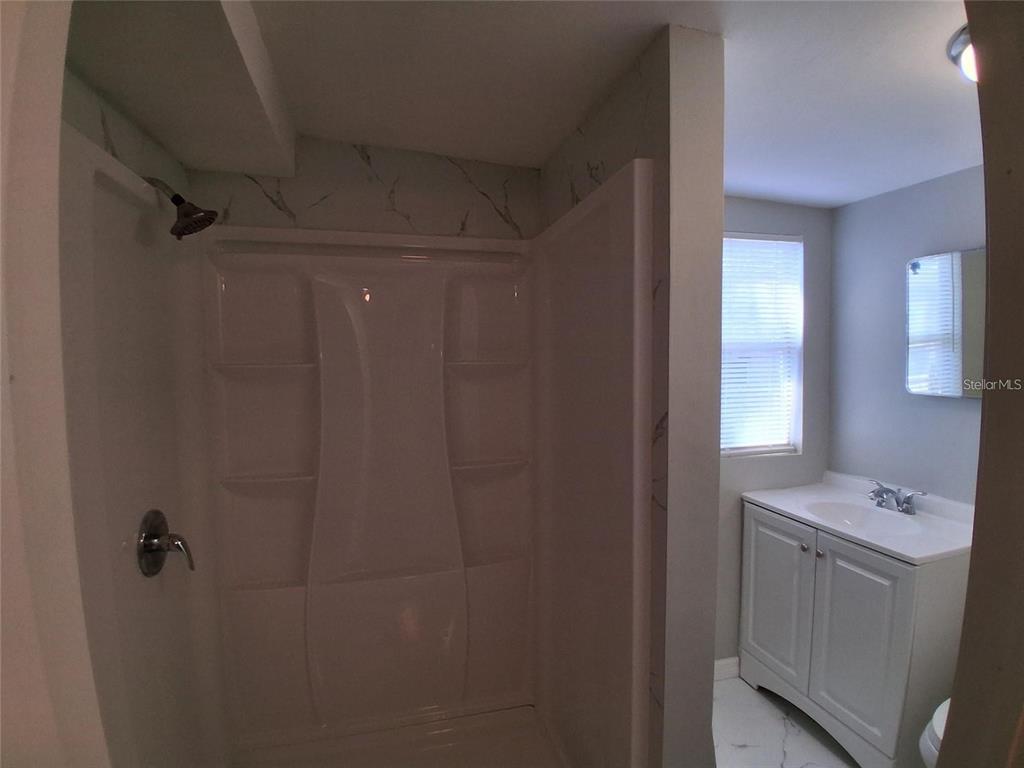 A bathroom features a white shower stall, a vanity with a sink, and marble-patterned walls — 506 N MACDILL AVENUE, TAMPA, FL