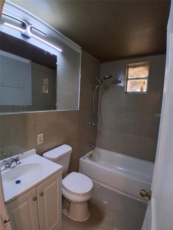 A bathroom features a vanity, toilet, and a tiled shower-tub combination with a small window — 506 N MACDILL AVENUE, TAMPA, FL