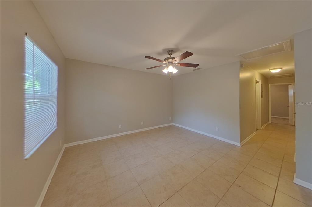 A room with light-colored tile flooring, beige walls, a ceiling fan, and a window — 4313 W BAY AVENUE, TAMPA, FL