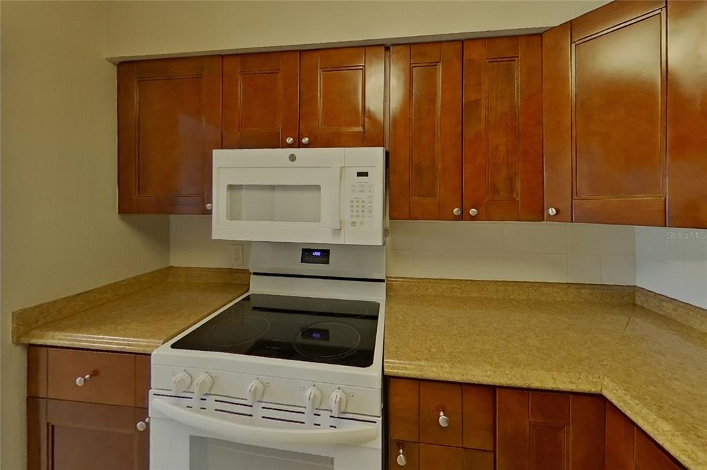 A kitchen features wooden cabinets, a white microwave, and a white electric stove — 4313 W BAY AVENUE, TAMPA, FL