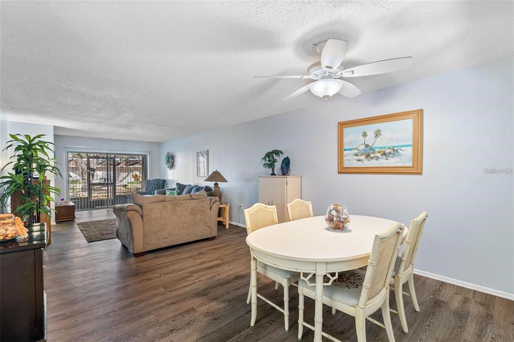 A dining area with a white table and chairs sits in front of a living room — 870 VIRGINIA STREET UNIT 104, DUNEDIN, FL
