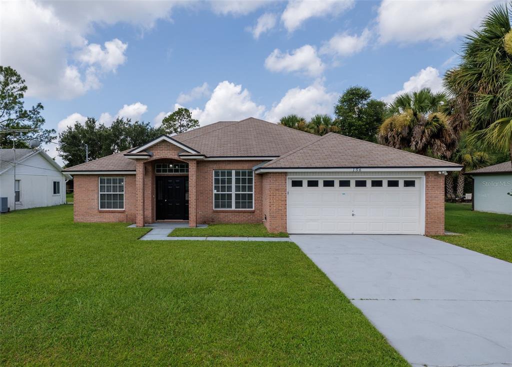 A single-story brick house with a two-car garage and a front entrance under a gable — 156 BARRINGTON DRIVE, PALM COAST, FL