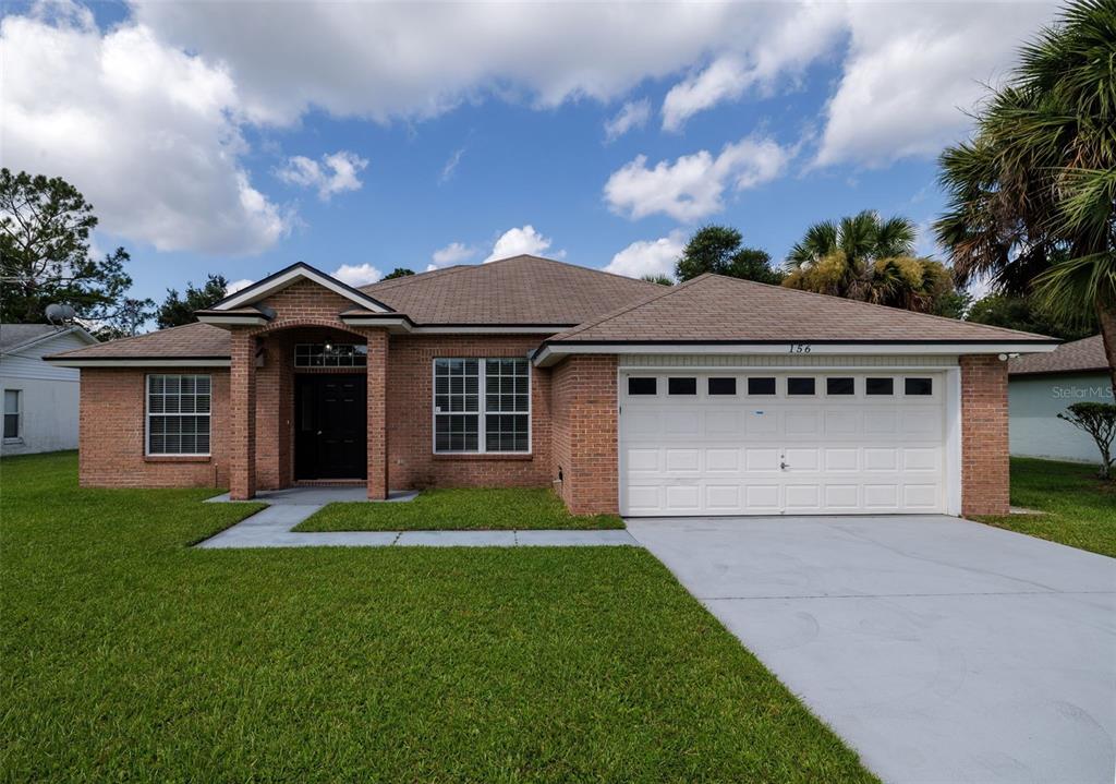 A single-story brick house with a two-car garage and a front lawn — 156 BARRINGTON DRIVE, PALM COAST, FL