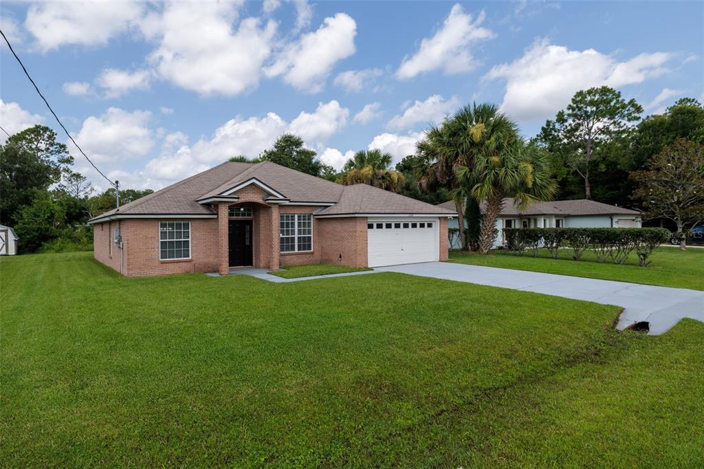 A single-story brick house with a two-car garage and a large front lawn — 156 BARRINGTON DRIVE, PALM COAST, FL