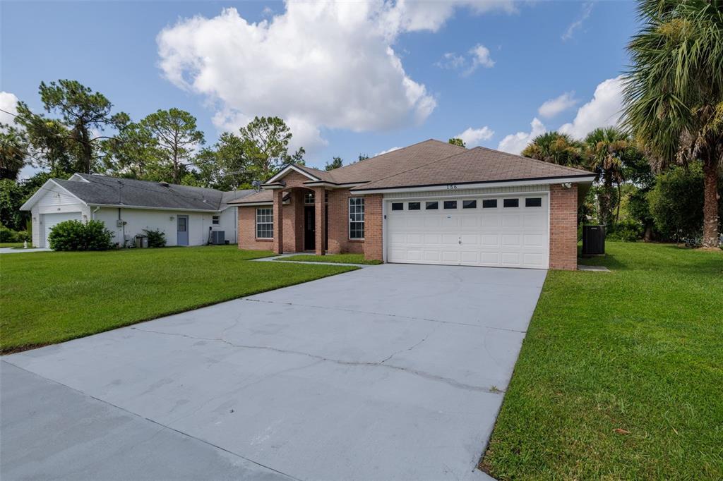 A single-story brick house with a two-car garage and a concrete driveway — 156 BARRINGTON DRIVE, PALM COAST, FL