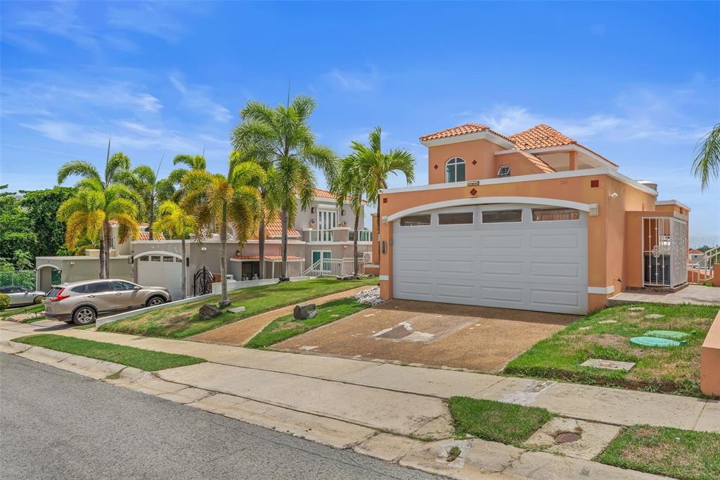 A two-story peach-colored house with a two-car garage and palm trees in the front yard — 65 THE VILLAGE AT THE HILL, CEIBA, PR