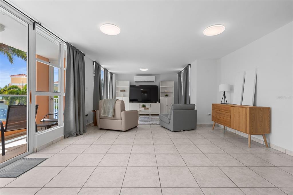 A living room with tile floors, a television, two armchairs, and a sliding glass door — 65 THE VILLAGE AT THE HILL, CEIBA, PR