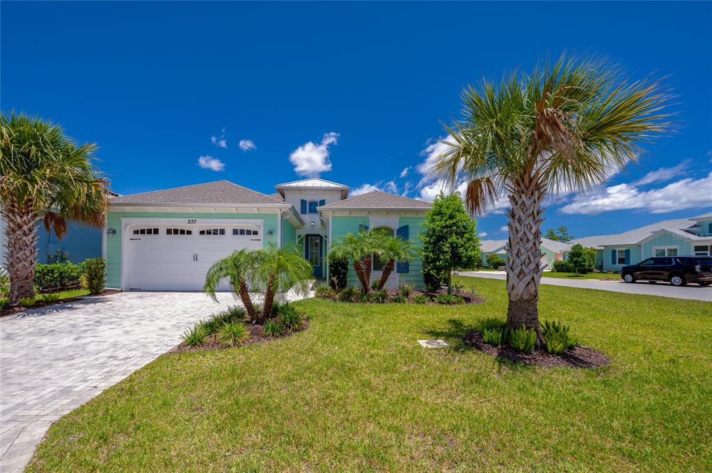 A light green single-story house with a white garage and palm trees in the yard — 237 SAND BAR LANE, DAYTONA BEACH, FL