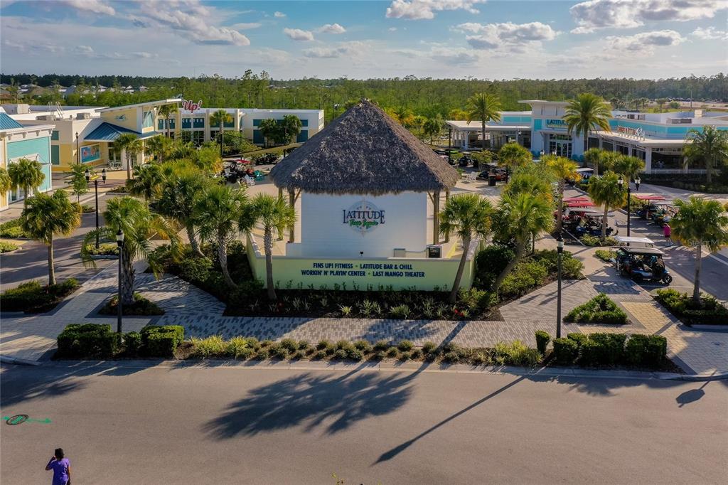 An aerial view shows a thatched-roof community center building surrounded by palm trees and golf carts — 237 SAND BAR LANE, DAYTONA BEACH, FL