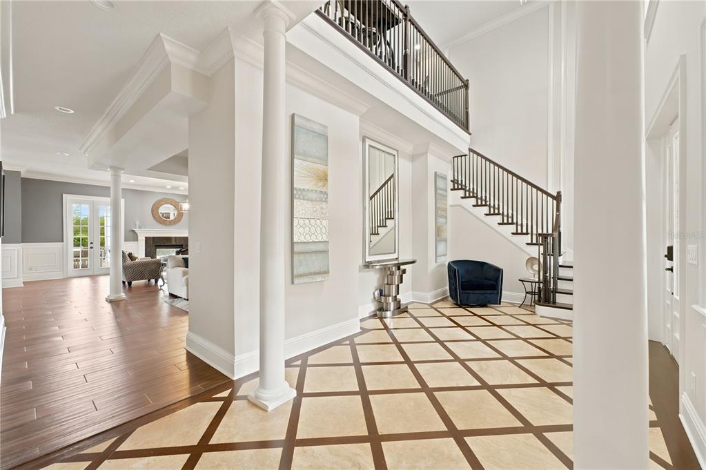 A grand foyer features a diamond-patterned tile floor, a staircase, and a view into a living room — 7481 GATHERING LOOP, REUNION, FL