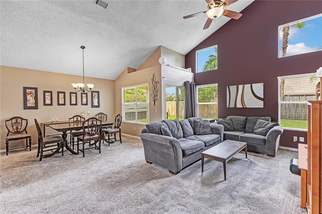 An entryway features a carpeted staircase, a gray armchair, a wooden bookshelf, and a front door — 779 MEADOWSIDE COURT, ORLANDO, FL