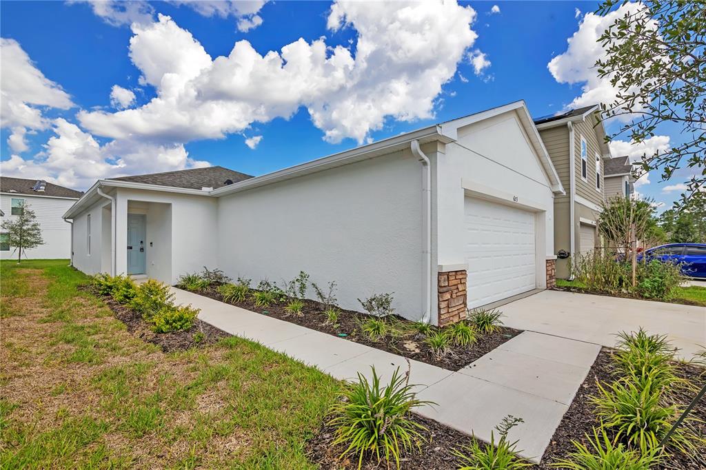 A white single-story house with a garage, a concrete walkway, and a blue front door — 673 TEVIOT ROAD, HAINES CITY, FL
