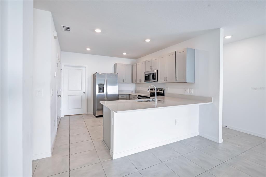 A kitchen with light gray cabinets, stainless steel appliances, and a white quartz breakfast bar — 673 TEVIOT ROAD, HAINES CITY, FL