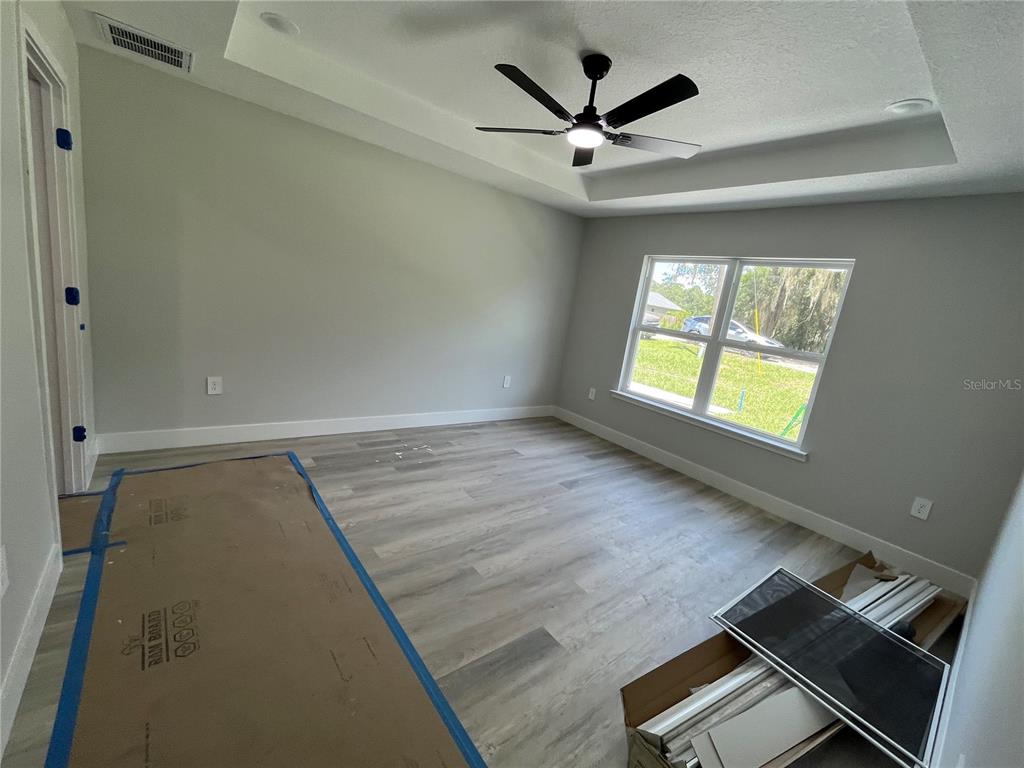 A bright dining area features light wood-look flooring, a modern chandelier, and sliding glass doors — 12728 SE 102ND TERRACE, BELLEVIEW, FL