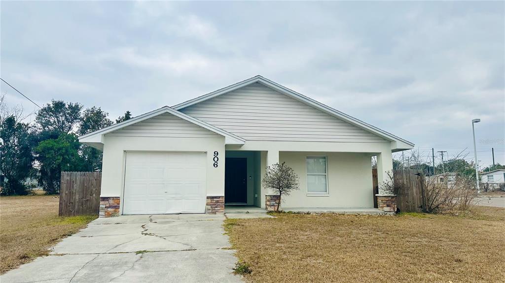 A single-story house with a white garage, beige siding, and a covered front porch — 906 SE 5TH STREET, MULBERRY, FL