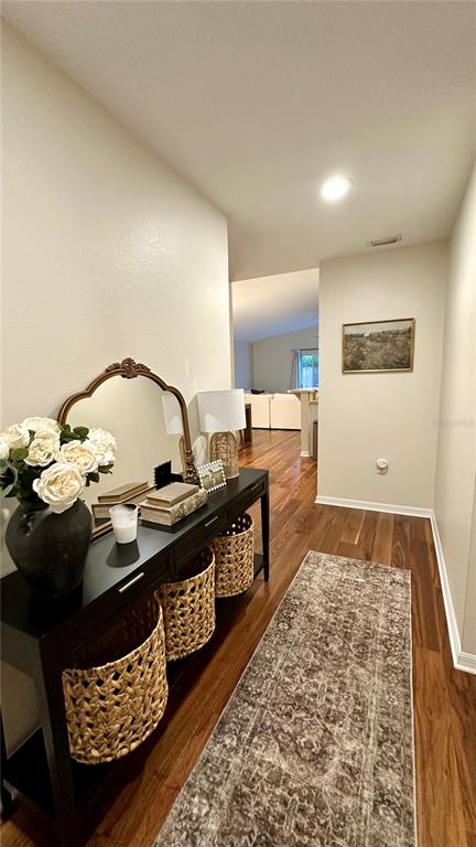 A hallway features a black console table with woven baskets, a mirror, and wood flooring — 906 SE 5TH STREET, MULBERRY, FL