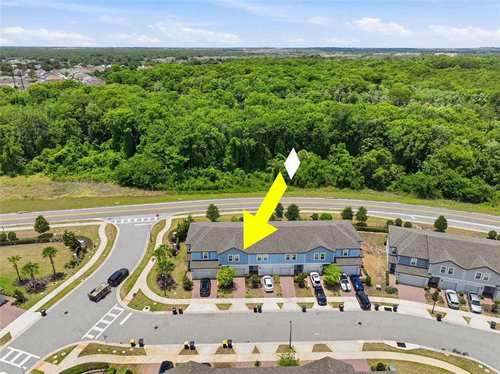 An aerial view shows a blue multi-unit townhouse building with a yellow arrow pointing down — 412 LEGACY LOOP, DAVENPORT, FL