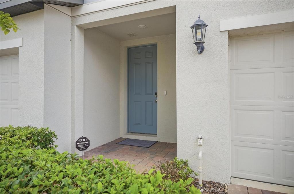 A blue front door is recessed within a white stucco exterior next to a garage — 412 LEGACY LOOP, DAVENPORT, FL
