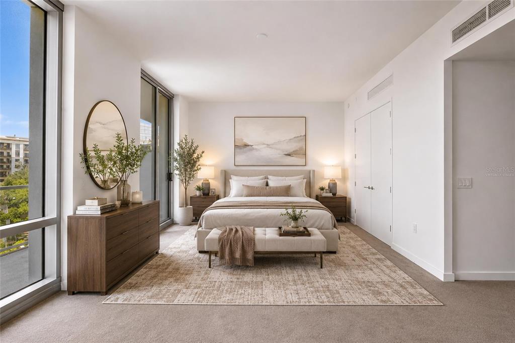 A modern bedroom features a bed, dresser, large mirror, and floor-to-ceiling windows with outdoor views — 400 CENTRAL AVENUE UNIT 407, ST PETERSBURG, FL