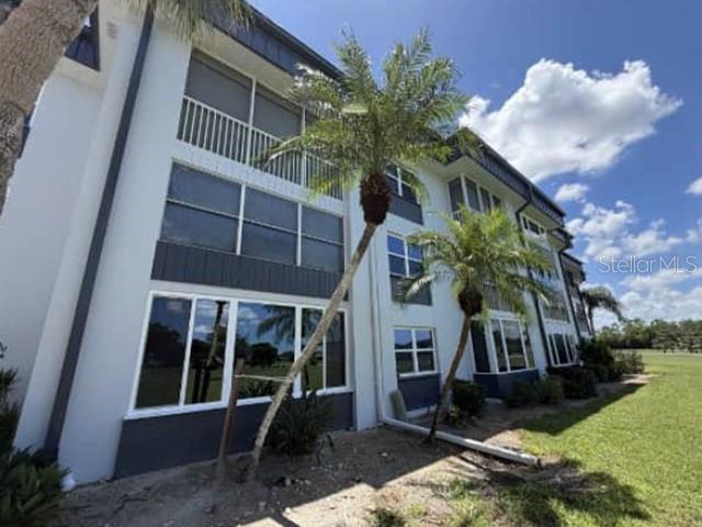 Exterior view of a multi-story apartment building with white walls and palm trees in front — 1740 PINE VALLEY DRIVE UNIT 205, FORT MYERS, FL