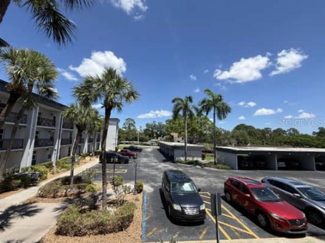 An exterior view of a multi-story apartment building with palm trees and a parking lot — 1740 PINE VALLEY DRIVE UNIT 205, FORT MYERS, FL
