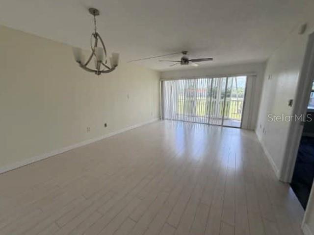 An empty living room features light wood-look flooring, a ceiling fan, and a large sliding door — 1740 PINE VALLEY DRIVE UNIT 205, FORT MYERS, FL