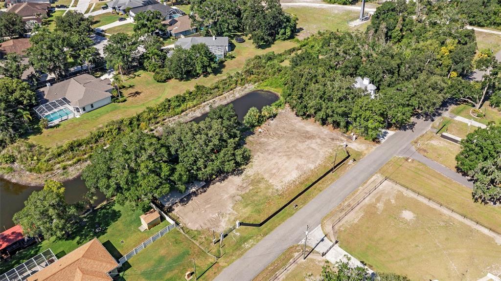 An aerial view shows a vacant, partially wooded residential lot next to a small pond — 5030 DUQUE ROAD, LUTZ, FL