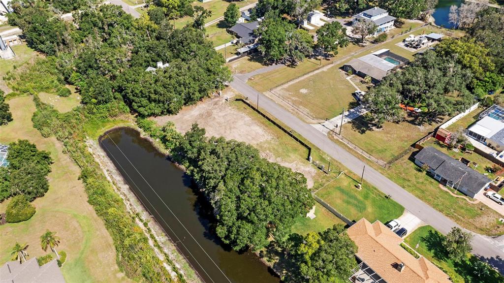 An aerial view shows a vacant lot next to a pond and residential houses — 5030 DUQUE ROAD, LUTZ, FL