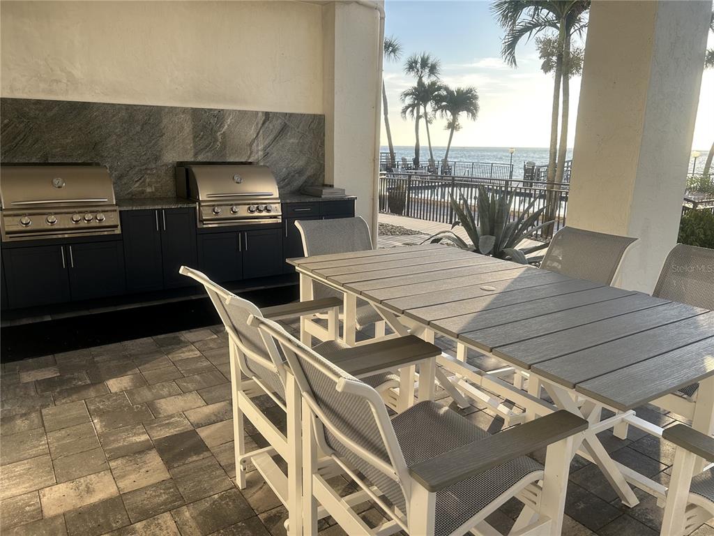 An outdoor kitchen with two stainless steel grills overlooks a patio and the ocean — 4822 OCEAN BOULEVARD UNIT 3D, SARASOTA, FL