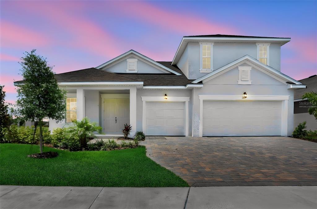 A two-story house with a three-car garage and a paved driveway at sunset — 7388 SEA MANATEE STREET, PARRISH, FL