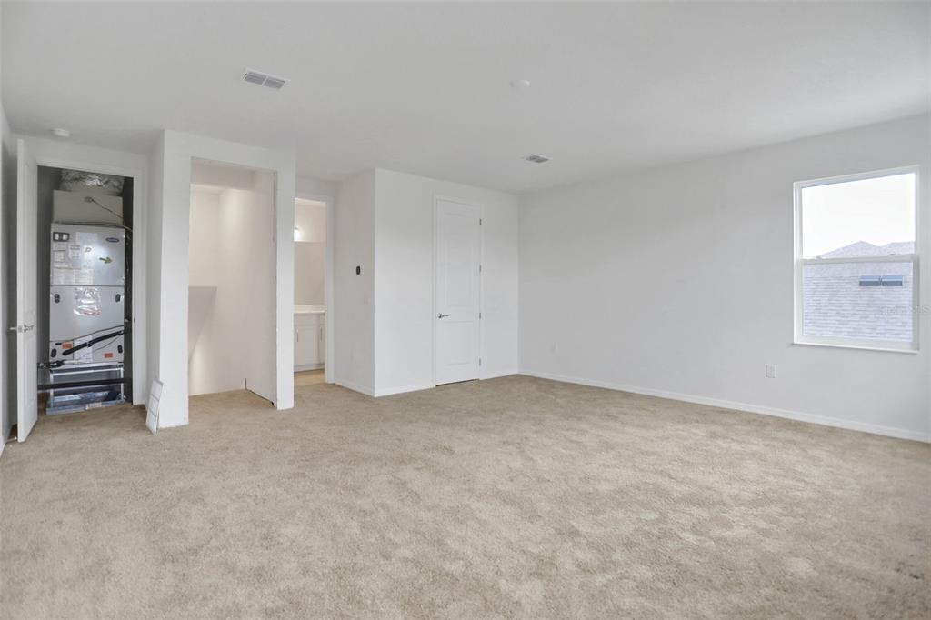 An empty carpeted bedroom features a utility closet with an HVAC unit and a window — 7388 SEA MANATEE STREET, PARRISH, FL