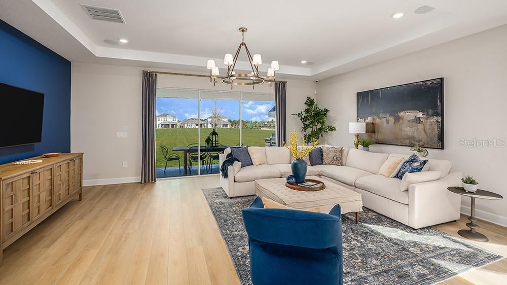 A living room features a blue accent wall, a sectional sofa, and a sliding glass door — 10859 ECLIPSE STREET, SARASOTA, FL