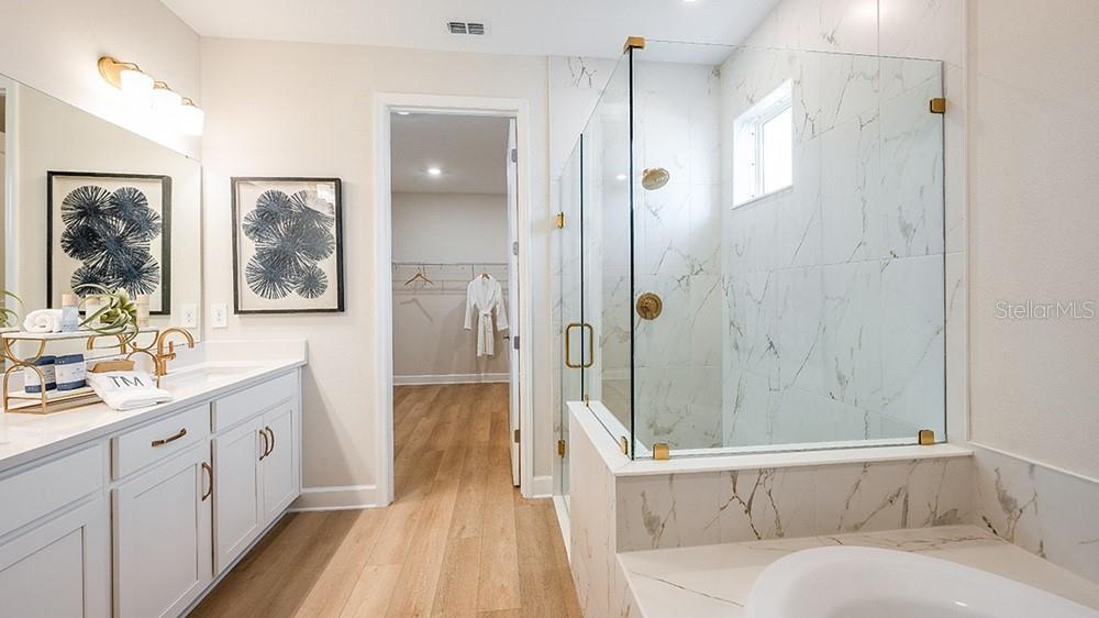 A bathroom features a white vanity, a glass-enclosed shower with marble tile, and wood flooring — 10859 ECLIPSE STREET, SARASOTA, FL