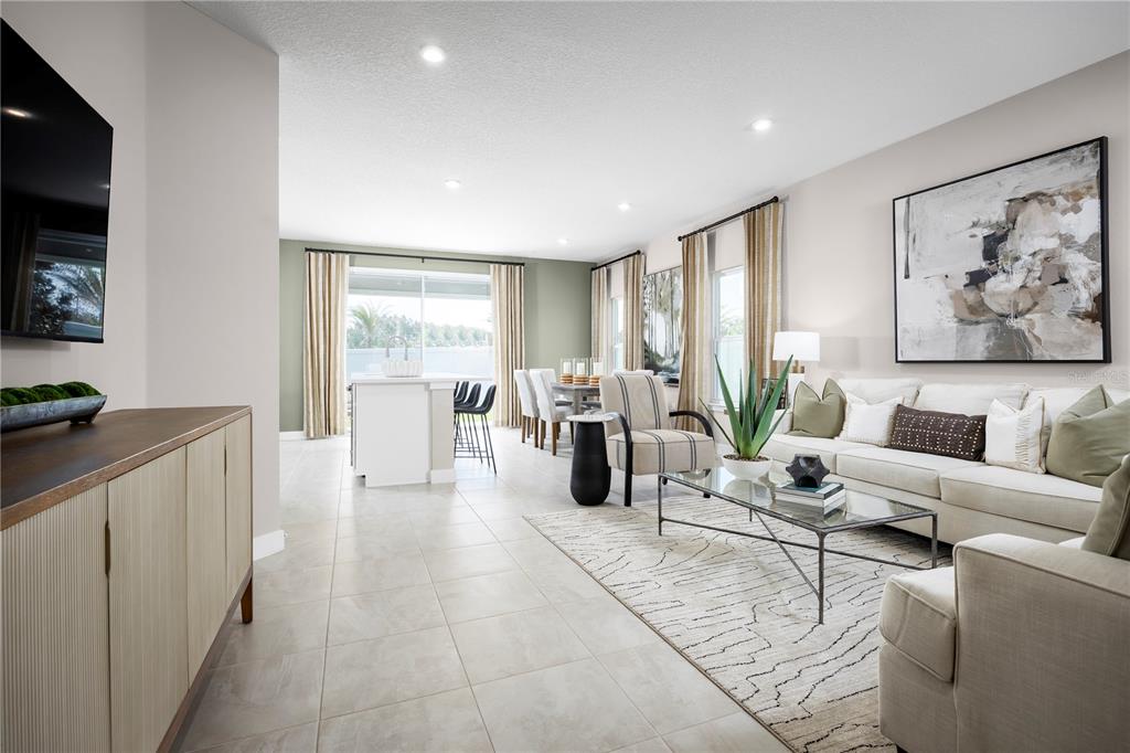A bright open-concept living and dining area features tile floors, neutral furniture, and large windows — 1768 KENDALL POINTE PLACE, MELBOURNE, FL