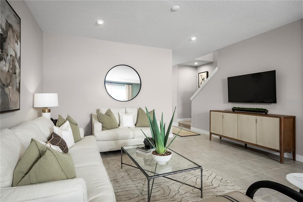 A living room features a white sofa, a glass coffee table, and a wall-mounted television — 1768 KENDALL POINTE PLACE, MELBOURNE, FL