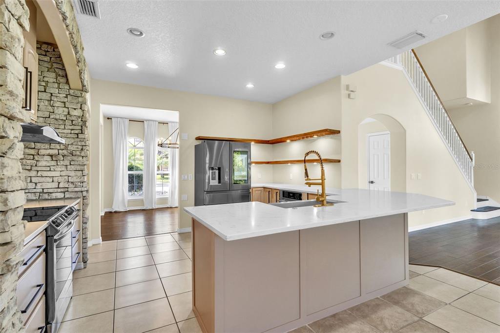 A dining area with wood flooring and a large chandelier connects to a kitchen — 4617 PATRICIA ANN COURT, ORLANDO, FL