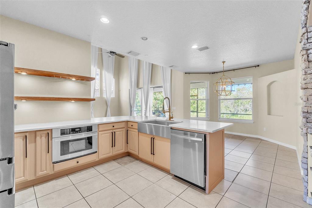 A kitchen features a stone-arched stove alcove, white quartz countertops, and a gray island — 4617 PATRICIA ANN COURT, ORLANDO, FL