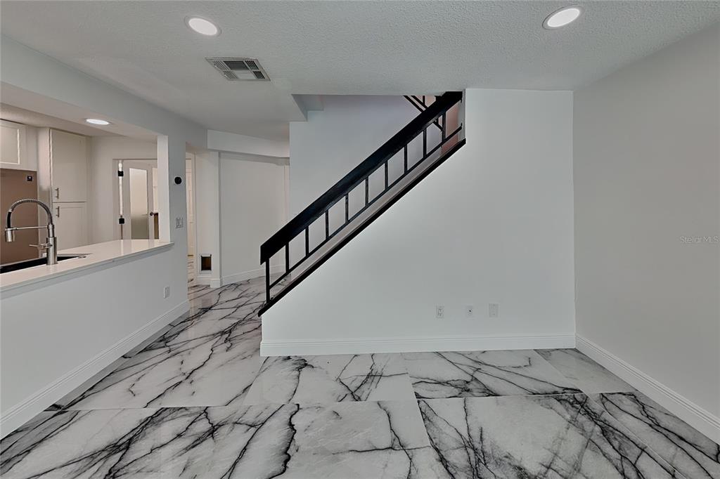An interior view of a room featuring white walls, recessed lighting, and marble-patterned tile flooring — 8212 CITRUS CHASE DRIVE, ORLANDO, FL