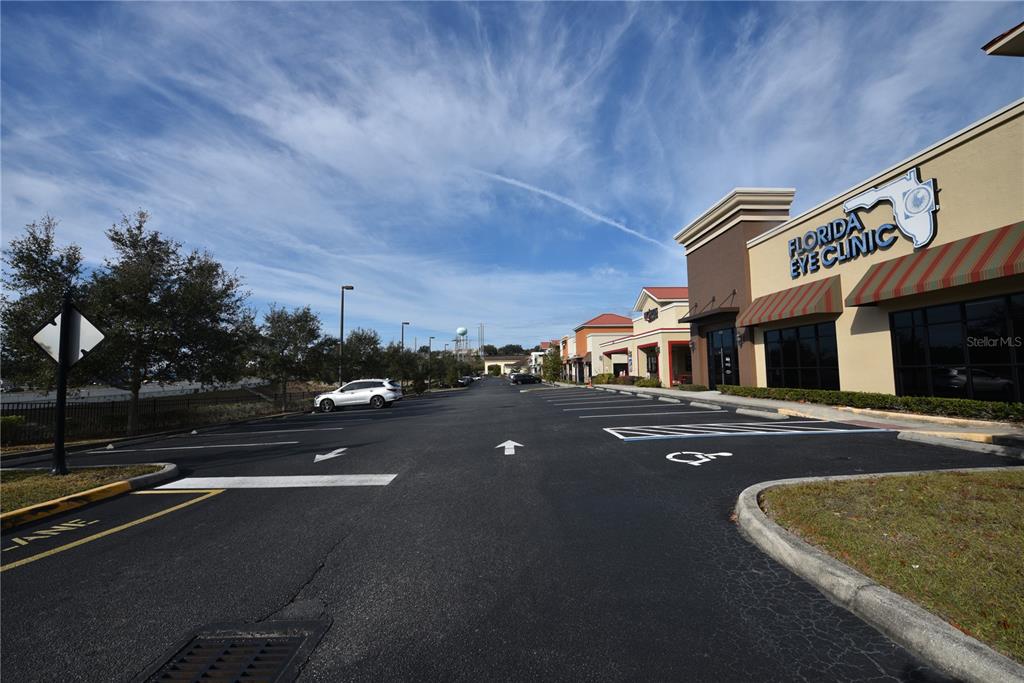 An exterior view of a commercial strip mall parking lot with a Florida Eye Clinic — 2460 E HIGHWAY 50, CLERMONT, FL