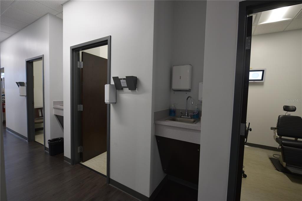 A medical office hallway features multiple exam rooms, a sink station, and dark wood flooring — 2460 E HIGHWAY 50, CLERMONT, FL