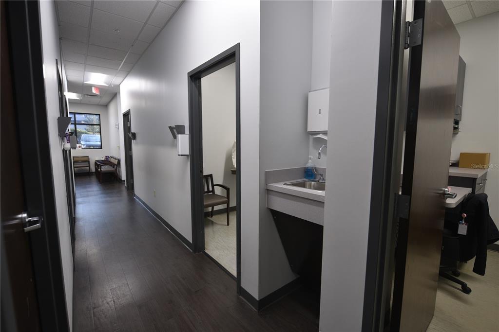 A hallway in a medical office features dark wood flooring, gray walls, and a small sink — 2460 E HIGHWAY 50, CLERMONT, FL